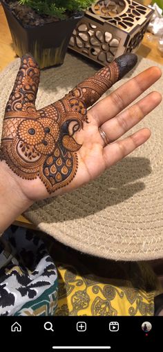 a person's hand with henna on it and some plants in the background