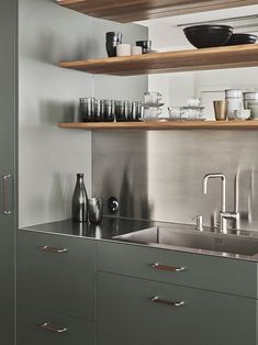 a kitchen with stainless steel cabinets and shelving above the sink is filled with dishes