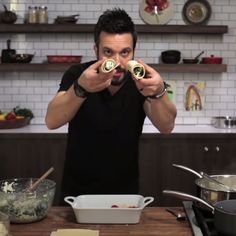 a man is holding two gold objects in front of his face as he looks at the camera