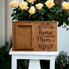 a wooden box with flowers in it sitting on top of a white chair next to some yellow roses