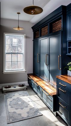 a kitchen with blue cabinets and wooden counter tops in front of a white rug on the floor