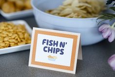 fish n'chips are sitting on the table next to bowls of food and flowers