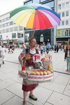 a man holding an umbrella over his head while standing in the street with donuts