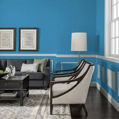 a living room with blue walls and white trim around the couches, coffee table