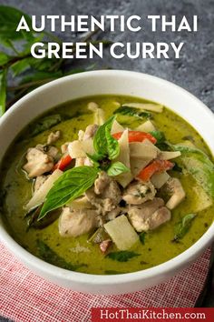 a white bowl filled with green curry next to a red and white checkered napkin