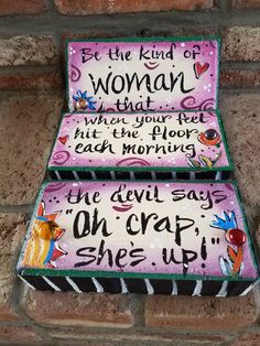 two hand painted signs on the side of a brick wall that says, let the kind of woman that when your feet hit the floor each morning