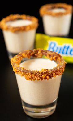 Three shot glasses with chocolate and crushed candy bar coated rims filled with light brown Butterfinger shots. Butterfinger Shots, Baileys Recipes Drinks, Chocolate Pudding Shots, Fried Dog, Jam Donut, Tasty Cocktails, Baileys Recipes, Butterfinger Candy, Dessert Shots