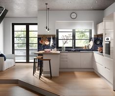 a modern kitchen with white cabinets and wood flooring is seen in this image from the stairs leading up to the living room