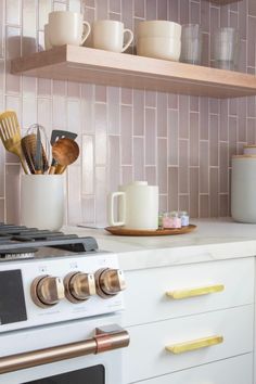 a stove top oven sitting inside of a kitchen next to a white counter topped with pots and pans