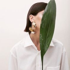 a woman is holding a green leaf in front of her face