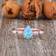 an opal and diamond ring sitting on top of a wooden table next to pumpkins