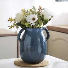 a blue vase filled with white flowers on top of a table