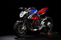 a red, white and blue motorcycle is parked on a black background with its lights on