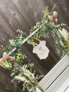 two vases filled with flowers and greenery next to a sign that says welcome