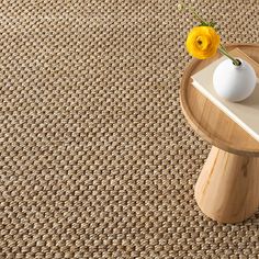 a vase with yellow flowers on top of a wooden table