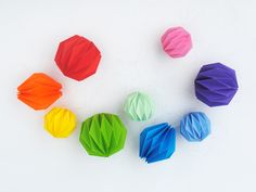 colorful paper balls arranged in a circle on a white surface with one being folded and the other is unzipped