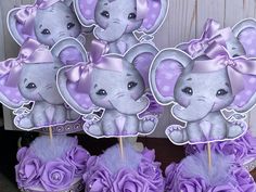 there are purple cupcakes that have elephants on them and flowers in the middle