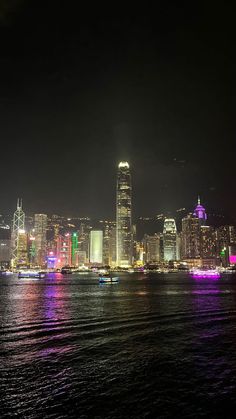 the city skyline is lit up at night, with bright lights on it's skyscrapers