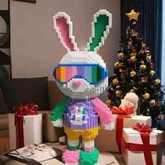 a christmas tree is in the background with presents around it and a lego bunny standing next to it