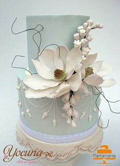 a blue and white wedding cake with flowers on top