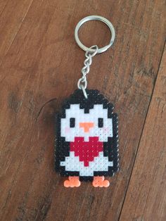 a penguin keychain is shown on a wooden surface