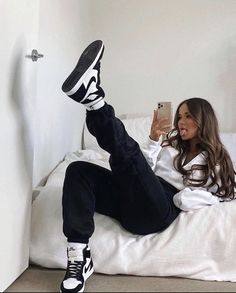 a woman laying on top of a bed with her feet up and holding a cell phone