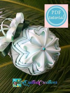 a white ornament with green ribbon and bow sitting on top of a palm tree