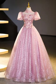 a pink dress on display in front of a white wall with stairs and lights behind it