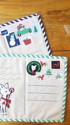 two envelopes with christmas stickers on them sitting on a wooden table next to each other