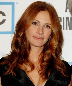 a woman with long red hair wearing a black dress