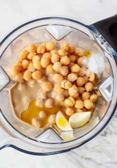 a blender filled with chickpeas and sauce on top of a marble counter