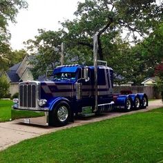 a large blue semi truck parked on the side of a road in front of a house