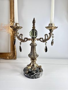 an ornate candelabra with two candles on it in front of a mirror