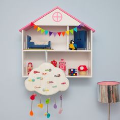 a doll house with toys hanging from it's sides and a shelf on the wall