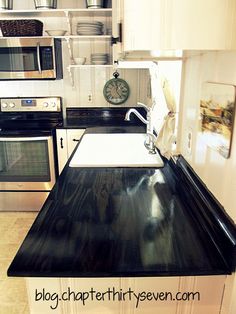 a kitchen with white cabinets and black counter tops, stainless steel appliances and an oven