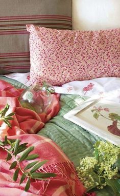 a bed with pink and green sheets, pillows and pictures on the wall above it