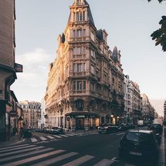 an old building on the corner of a street with cars parked in front of it