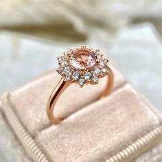 a pink diamond ring sitting on top of a velvet box