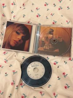 two cd's sitting on top of a bed next to each other, one with an image of a woman