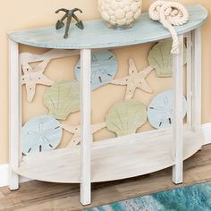 a blue and white console table with sea shells on the top, next to a rug