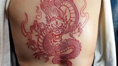 a red dragon tattoo on the back of a man's left arm and leg