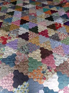 an old quilt is laying on top of a tablecloth that has hexagons all over it