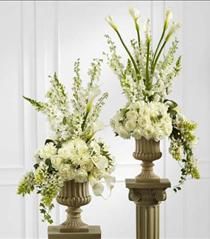 two vases filled with white flowers sitting next to each other