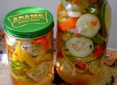 two jars filled with pickled vegetables sitting on top of a table next to each other