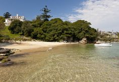 there is a boat that is in the water near some trees and sand on the beach