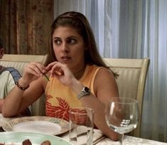 two people sitting at a table with plates of food in front of them and wine glasses on the table