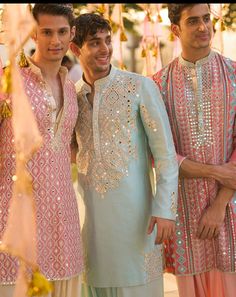 three men standing next to each other in ethnic clothing