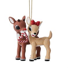 two ornaments are hanging from chains on a white background, one has a red bow and the other is a deer