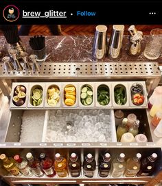 an assortment of drinks and condiments are arranged on a silver bar with marble counter top