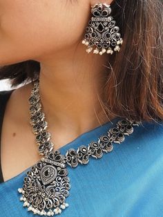 This jewellery set consists of an oxidised necklace and a pair of earringsOxidised silver-plated black artificial stones-studded jewellery set, secured with S-hook closureA pair of matching earrings, secured with a post-and-back closure Size & Fit Size: Necklace: 28.5 cm x 5.2 cm (Length x Width)Earrings: 4.5 cm x 3.3 cm(Length x Width) Material & Care Material: BrassStone type: Artificial StonesPlating: Silver-plated Care InstructionWipe your jewellery with a soft cloth after every useAlways store your jewellery in a flat box to avoid accidental scratchesKeep sprays and perfumes away from your jewelleryDo not soak your jewellery in waterClean your jewellery using a soft brush, dipped in jewellery cleaning solution only Dispatch within 7 days Oxidised Jewellery Set On Saree, Garba Fits, Oxidised Jewellery Earrings, Oxidised Jewellery Set, Studded Jewellery, Oxidised Necklace, Oxidized Jewellery, Oxidised Silver Jewelry, Fancy Jewelry Necklace